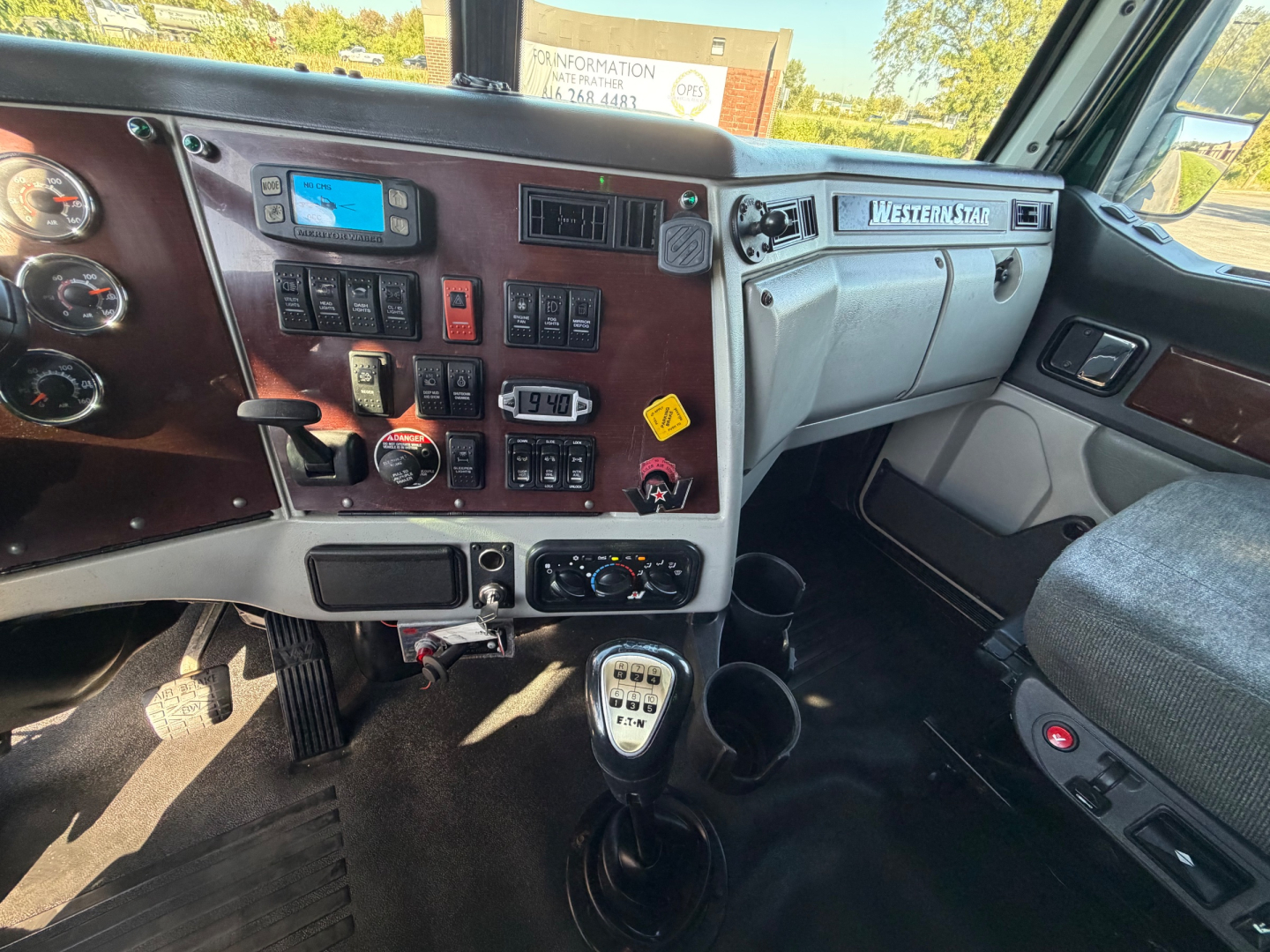 Dashboard and center console of a 2017 Western Star 5700XE with various switches, gauges, and a manual gear shifter.