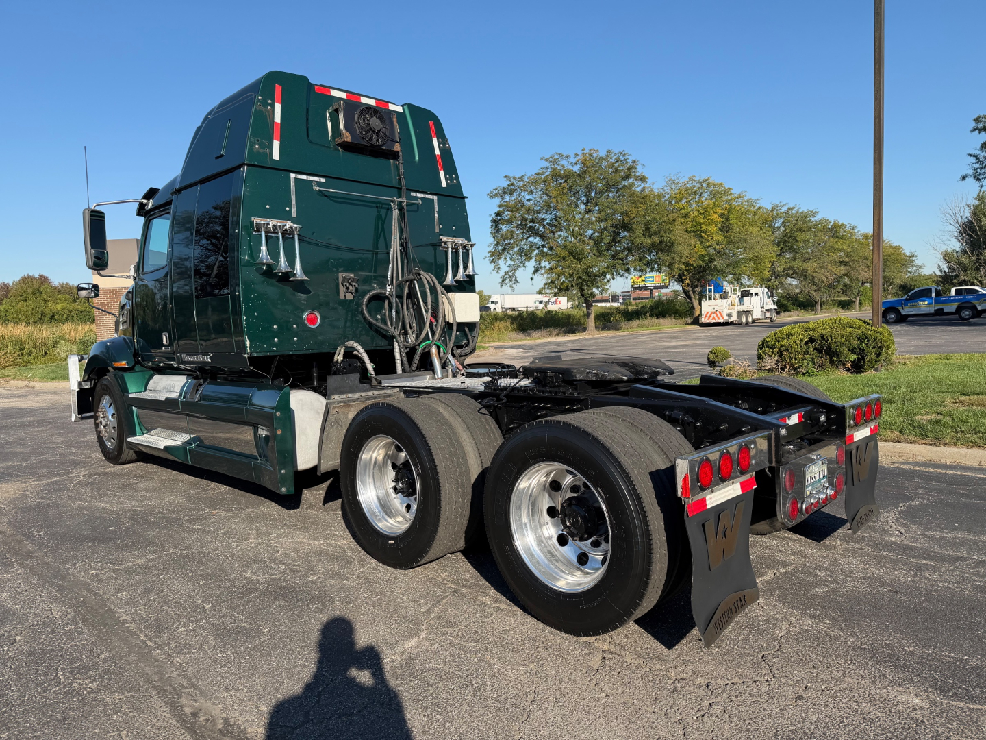 2017 Western Star 5700XE tractor-trailer chassis side rear view showing dual rear axles and fifth wheel, with green cab and storage compartments