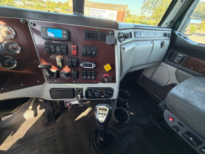 Dashboard and center console of a 2017 Western Star 5700XE with various switches, gauges, and a manual gear shifter.