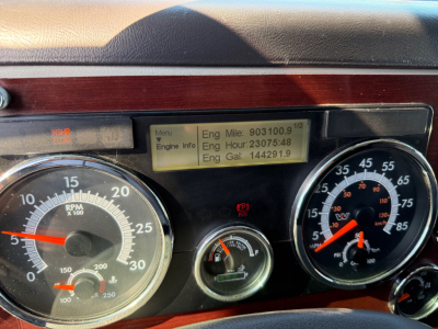 Dashboard of a 2017 Western Star 5700XE showing two large gauges (RPM and speedometer) with a central small gauge and a yellowed digital display panel.