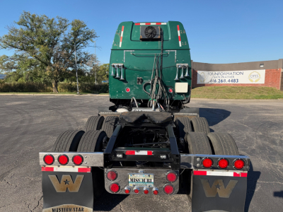 Rear view of a green Western Star 5700XE tractor chassis with Missouri license plate, dual rear axles, and various lights.