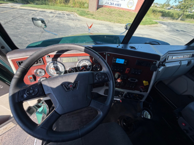 Wheel and dashboard of a Western Star 5700XE truck cab interior showing steering wheel, gauges, and control panel