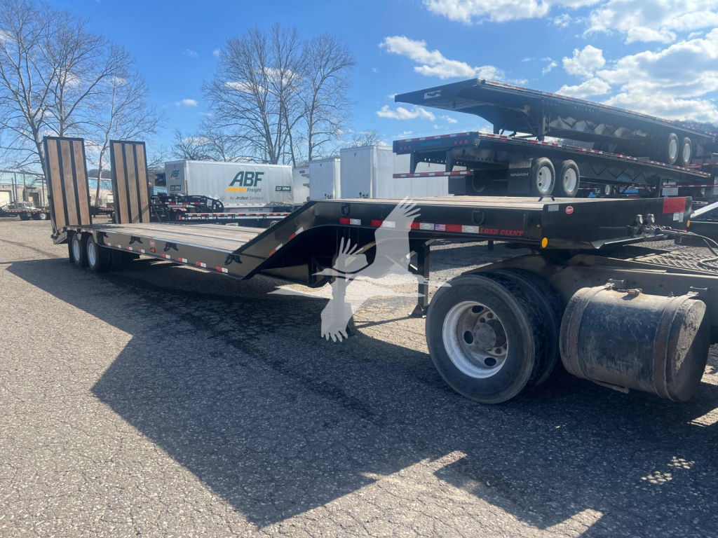 Trailer deck showing low-profile flatbed with gooseneck and wheels, VIN 7KYLB352XVED48526 visible on stock tag, ABF trailer in background.