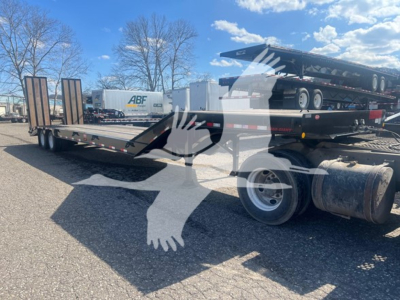 Trailer deck showing a Dorsey LB35-33Cs drop deck trailer with dual axles, black flatbed surface, and rear wheels visible.
