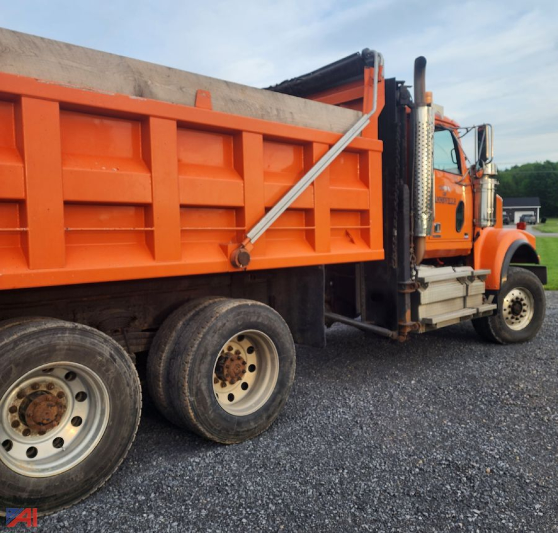 Orange Western Star 4900 SF dump truck with plows and sander showing side view and dual rear wheels.