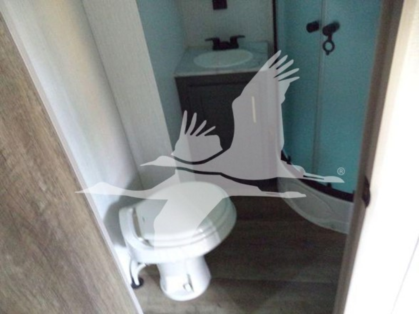 Trailer bathroom interior with sink, mirror, and toilet visible through doorway.