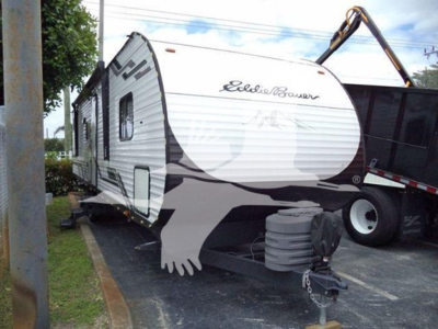 Travel trailer showing Eddie Bauer edition on the front with branding and exterior graphics, hitch area at the front, propane tank nearby.