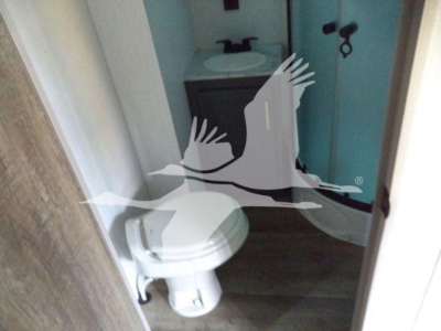 Trailer bathroom interior with sink, mirror, and toilet visible through doorway.