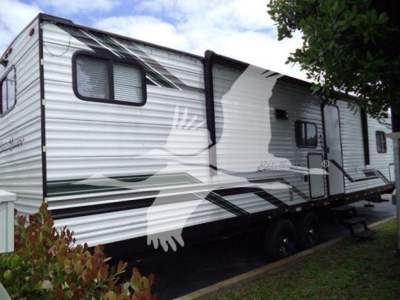 Travel trailer side with graphic design, windows, and entry door; no legible model text visible.