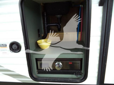 Trailer storage compartment with an integrated control panel and small oven-like drawer showing a knob and digital display.