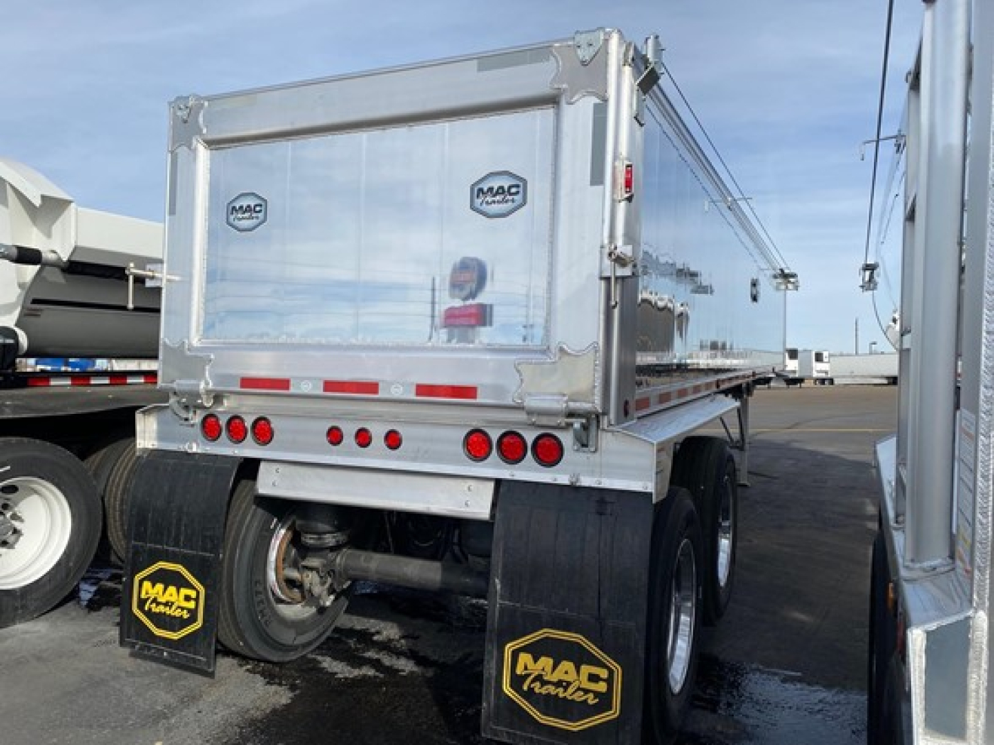 Dump trailer rear with aluminum sides and MAC trailer logos, dual rear axles, mud flaps, and taillights; VIN 150097341157 visible on listing.