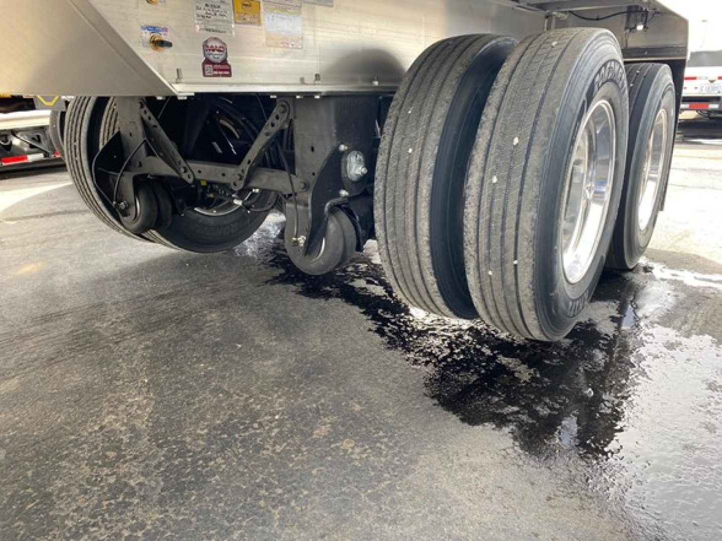 Trailer undercarriage showing dual rear axles with tires and suspension components.