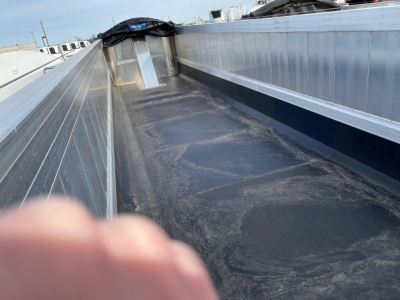 View of a new Mac Western lightweight aluminum end dump trailer bed showing the flat aluminum sidewalls and a black bed liner with a small ramp at the front.