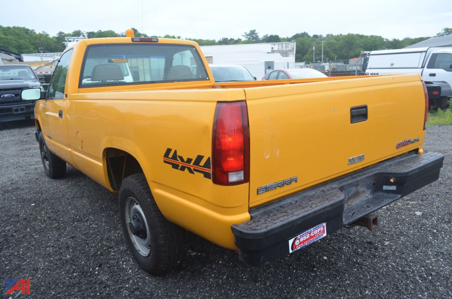 Rear-quarter view of a yellow 1995 GMC Sierra 2500 pickup truck with a long bed, showing badges and tailgate text, in a parking lot.