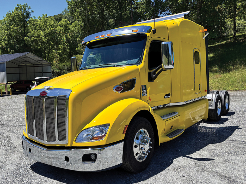 Peterbilt 579 UltraCab yellow semi tractor, side view showing grille, headlights, chrome bumper, fuel tanks, and sleeper cab.