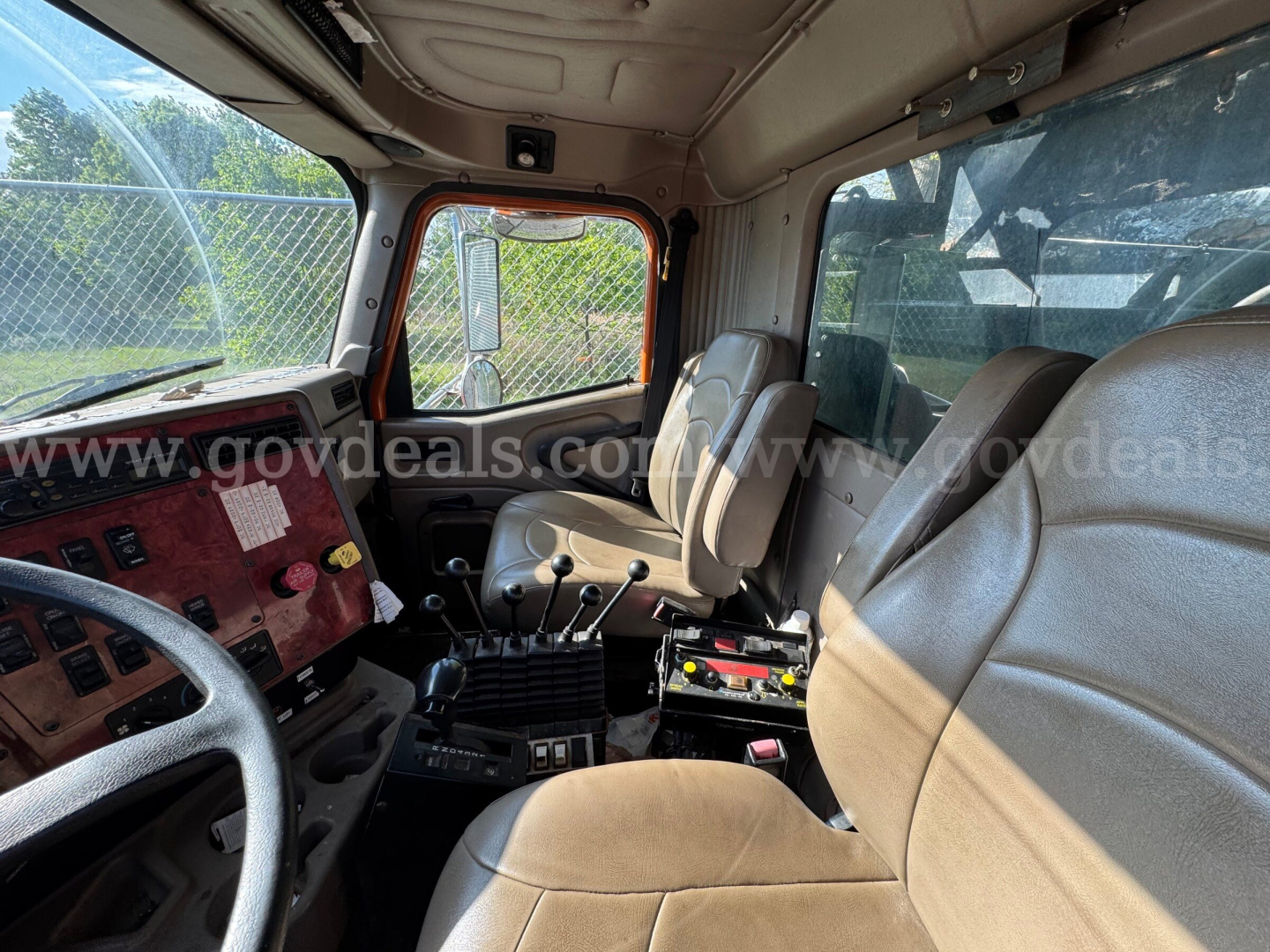 Cab interior of a 2004 International 5600i dump truck showing steering wheel, dash, and front seats with gear shifter and control panels.