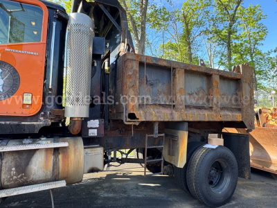 Dump truck bed and cab of a 2004 International 5600i with a rusted dump bed, visible exhaust stack, fuel tank, and dual rear wheels.