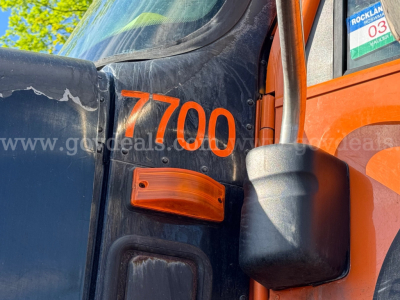Front door area of a 2004 International 5600i dump truck showing the number 7700 in orange on the black cab and an orange side marker light.