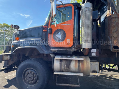 Truck cab side view of a 2004 International 5600i dump truck showing exhaust stack, fuel tank, and door decal with 7000 model badge.