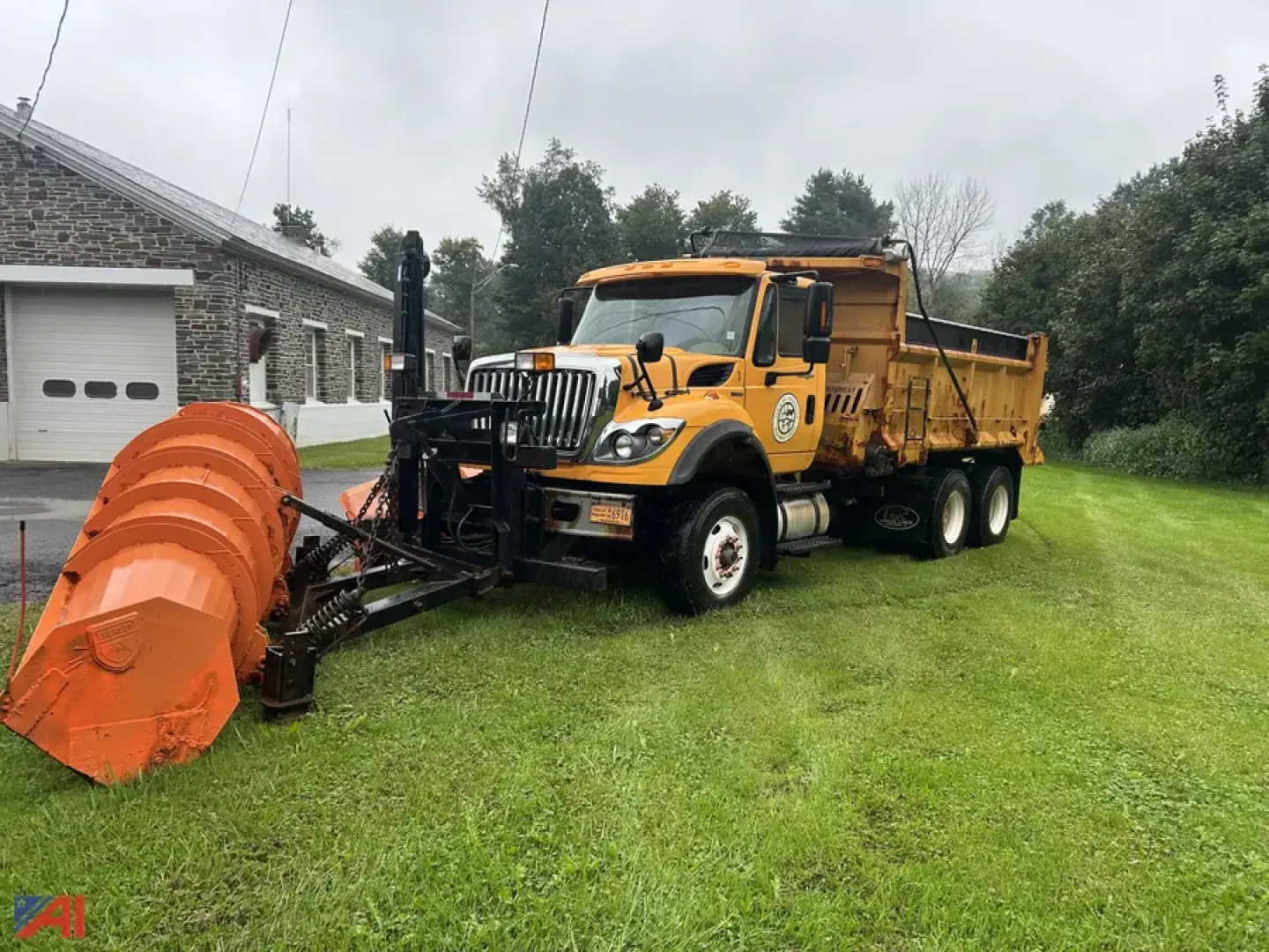Front and side view of a yellow 2011 International SF647 WorkStar dump truck with a large orange plow/wing attachment in the foreground.