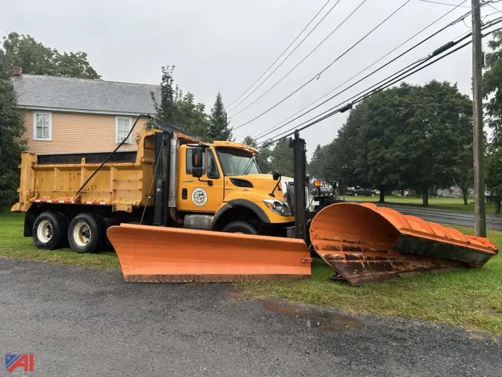 International WorkStar dump truck with plow and wing facing left, yellow cab, large orange plow blades in foreground.
