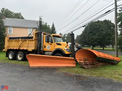 International WorkStar dump truck with plow and wing facing left, yellow cab, large orange plow blades in foreground.