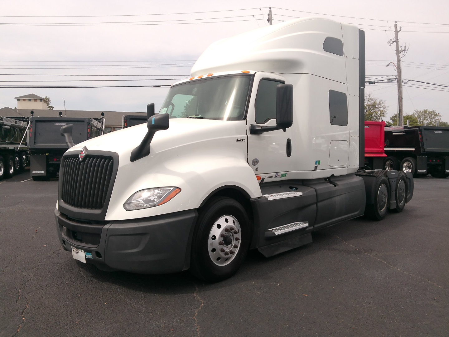 Truck side view showing 2023 International LT625 sleeper cab with white exterior, black bumper, and tandem rear axles.