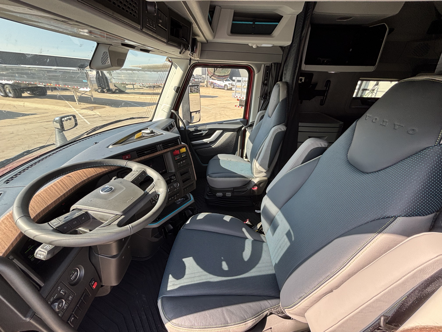Volvo VNL64T860 truck cabin interior with steering wheel, two captain seats, dashboard and overhead controls visible