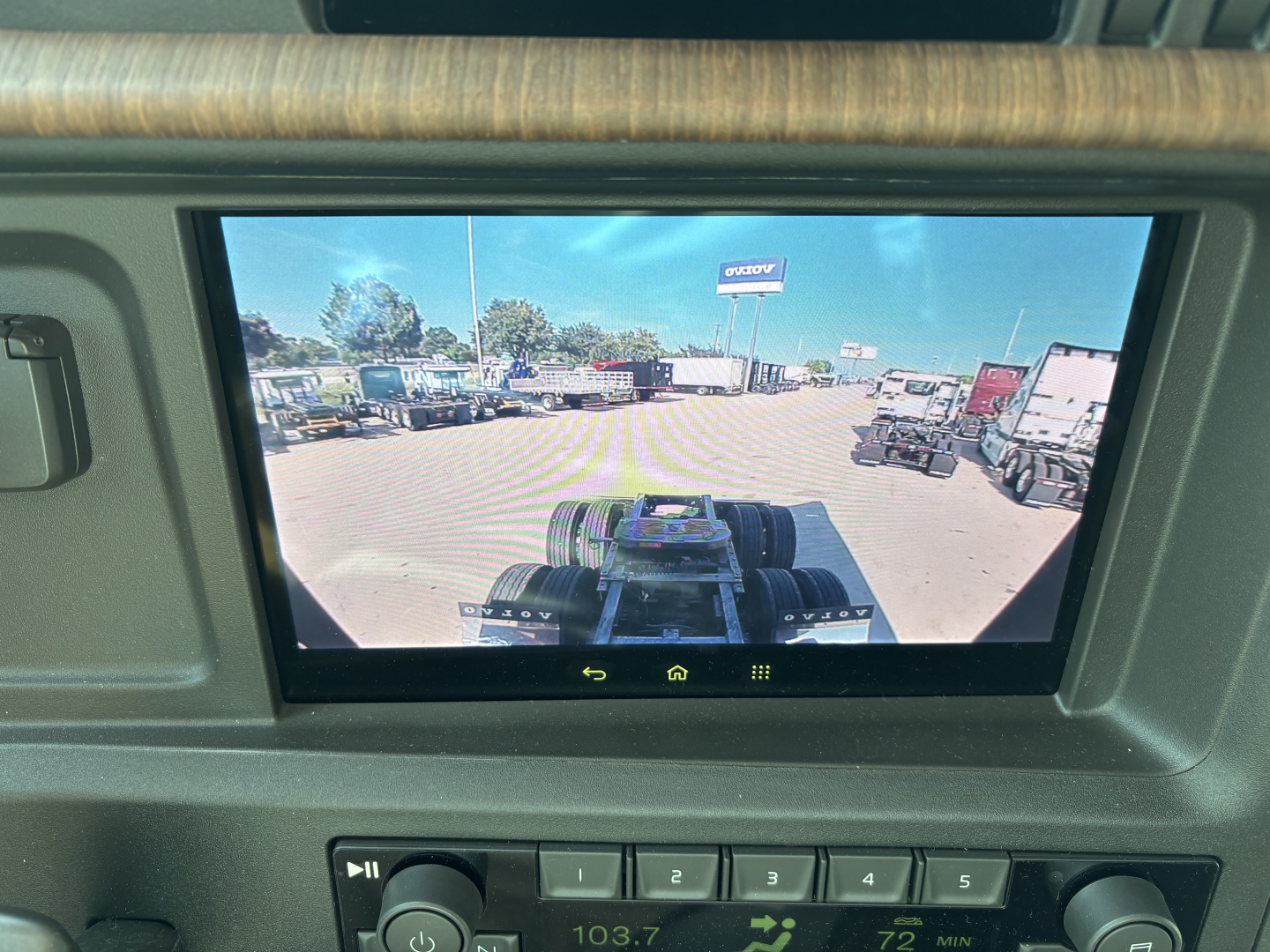 Volvo VNL64T860 dashboard display showing view from the cab with trucks in a dealership lot.