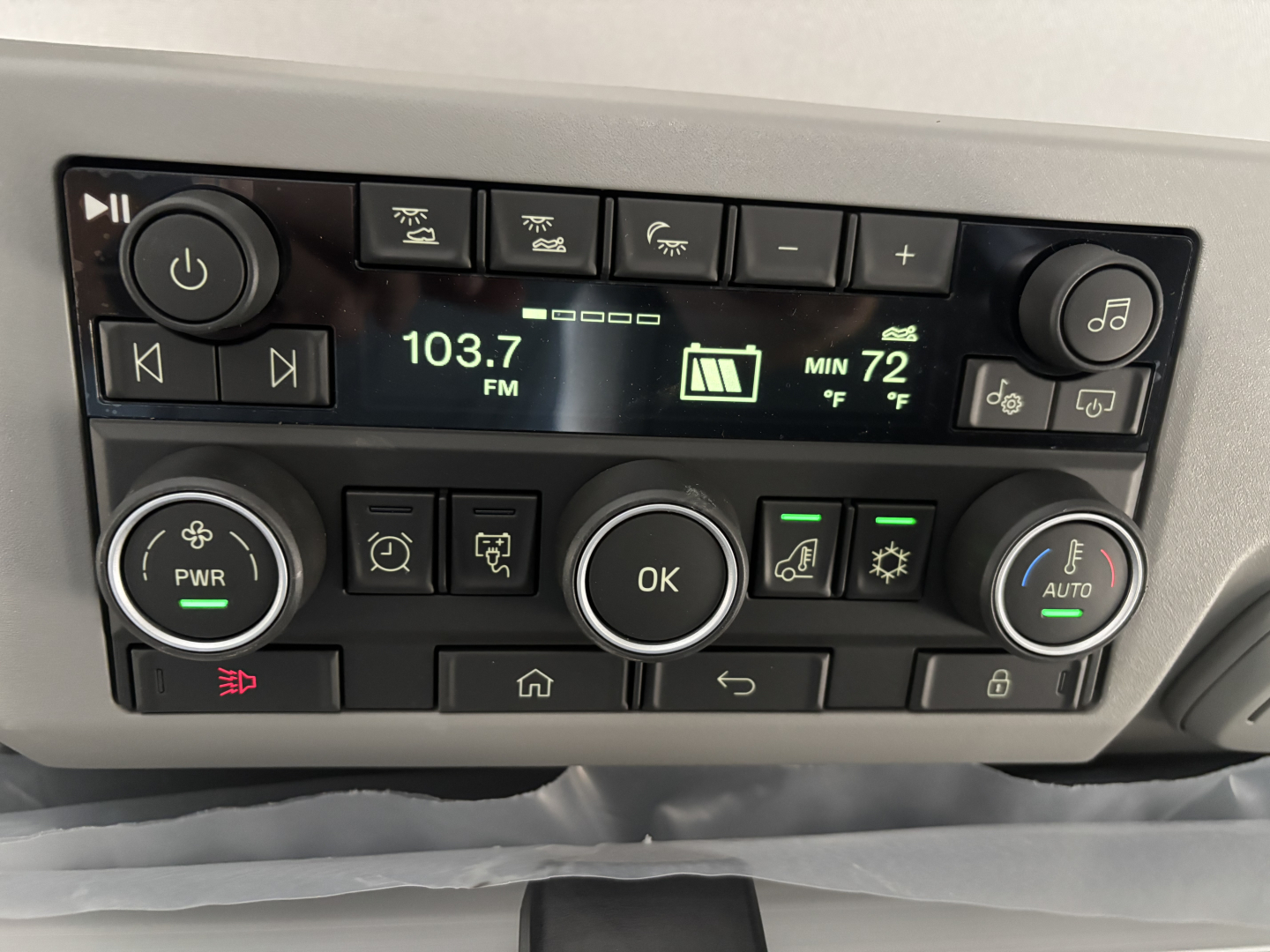 Dashboard of a new Volvo VNL64T860 showing radio display 103.7 FM and climate controls with multiple buttons.