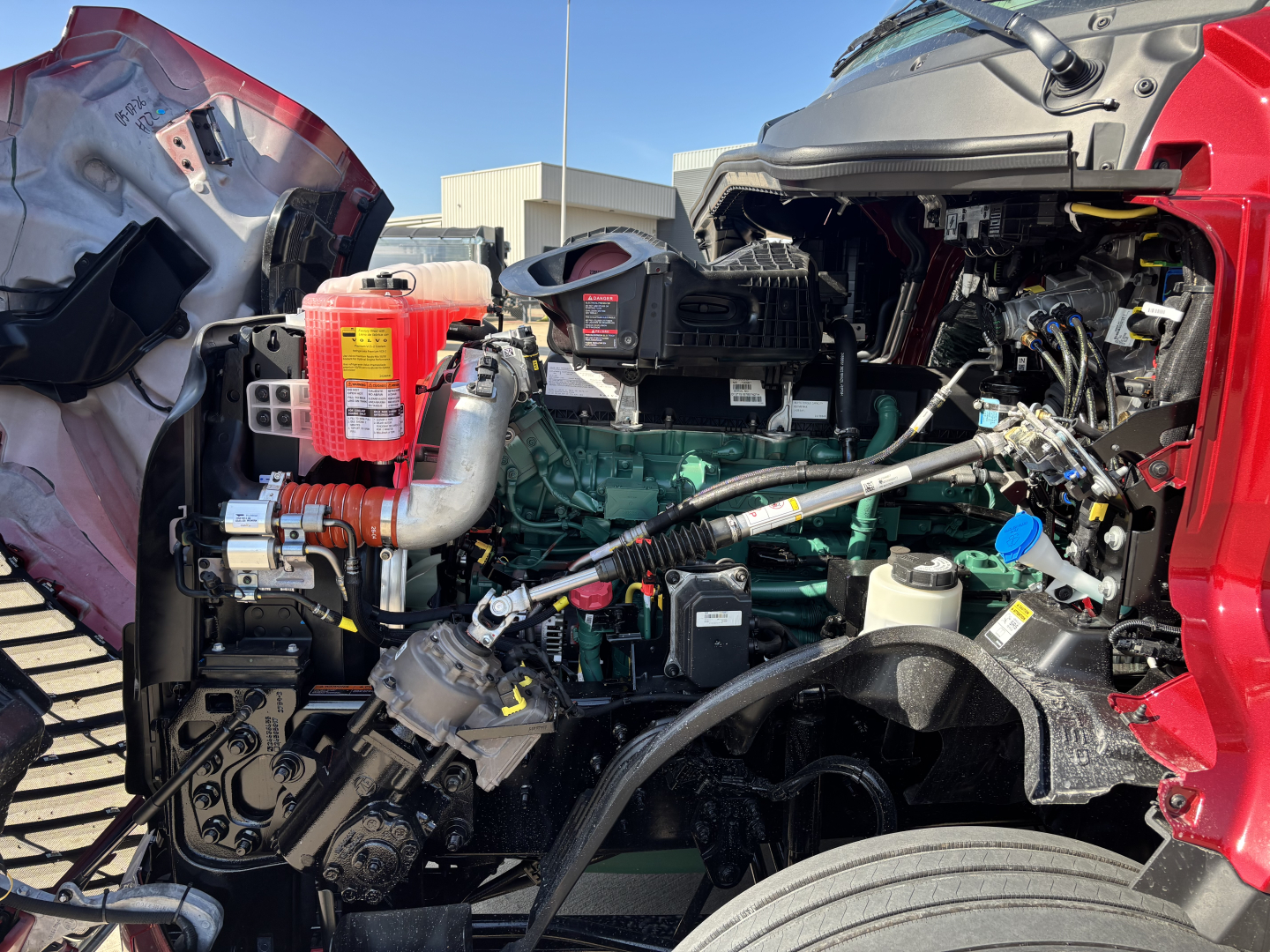 Volvo VNL64T860 engine bay showing green engine block, hoses, wiring, air intake, and various fluid reservoirs visible under open hood.