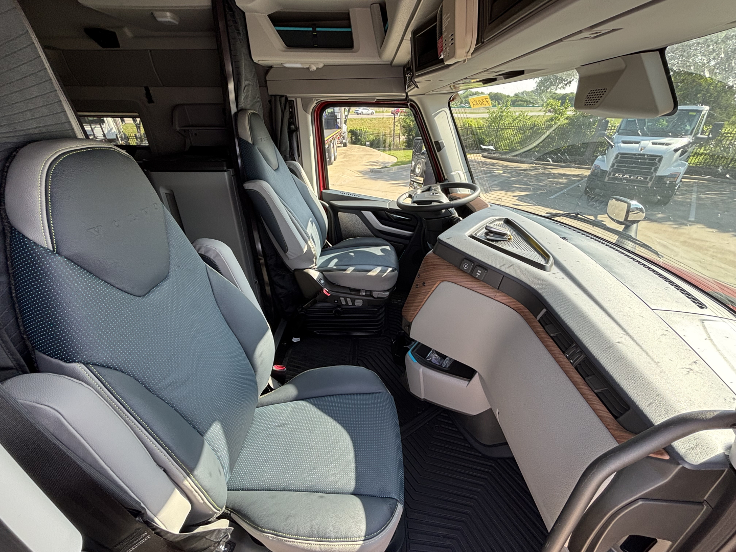 Volvo VNL interior cab view showing steering wheel, dashboard, driver seat, and passenger seat.