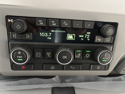 Dashboard of a new Volvo VNL64T860 showing radio display 103.7 FM and climate controls with multiple buttons.