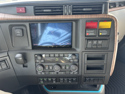 Dashboard view of a new 2027 Volvo VNL64T860 showing center touchscreen, climate controls, and various switches in a sleeper truck cab.