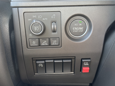 Volvo engine start-stop button and dashboard controls showing headlight dial and auxiliary switches in view.