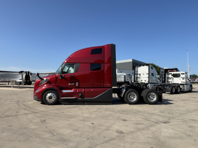 Volvo VNL64T860 truck in a parking lot showing a bright red sleeper cab and dual rear axles.