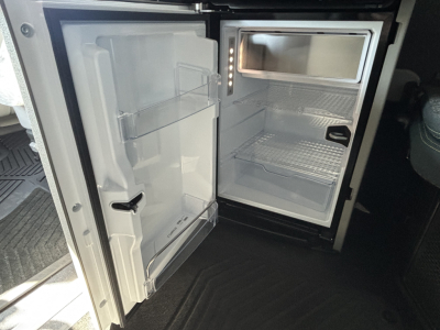 Fridge/freezer in Volvo VNL cab showing open refrigerator with shelves and door compartments.