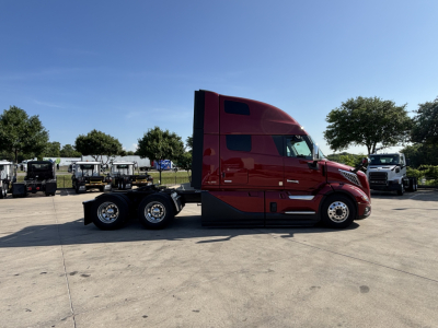 Red Volvo VNL sleeper cab tractor tractor side view showing bunk, three axles, large windows, and chrome wheels.