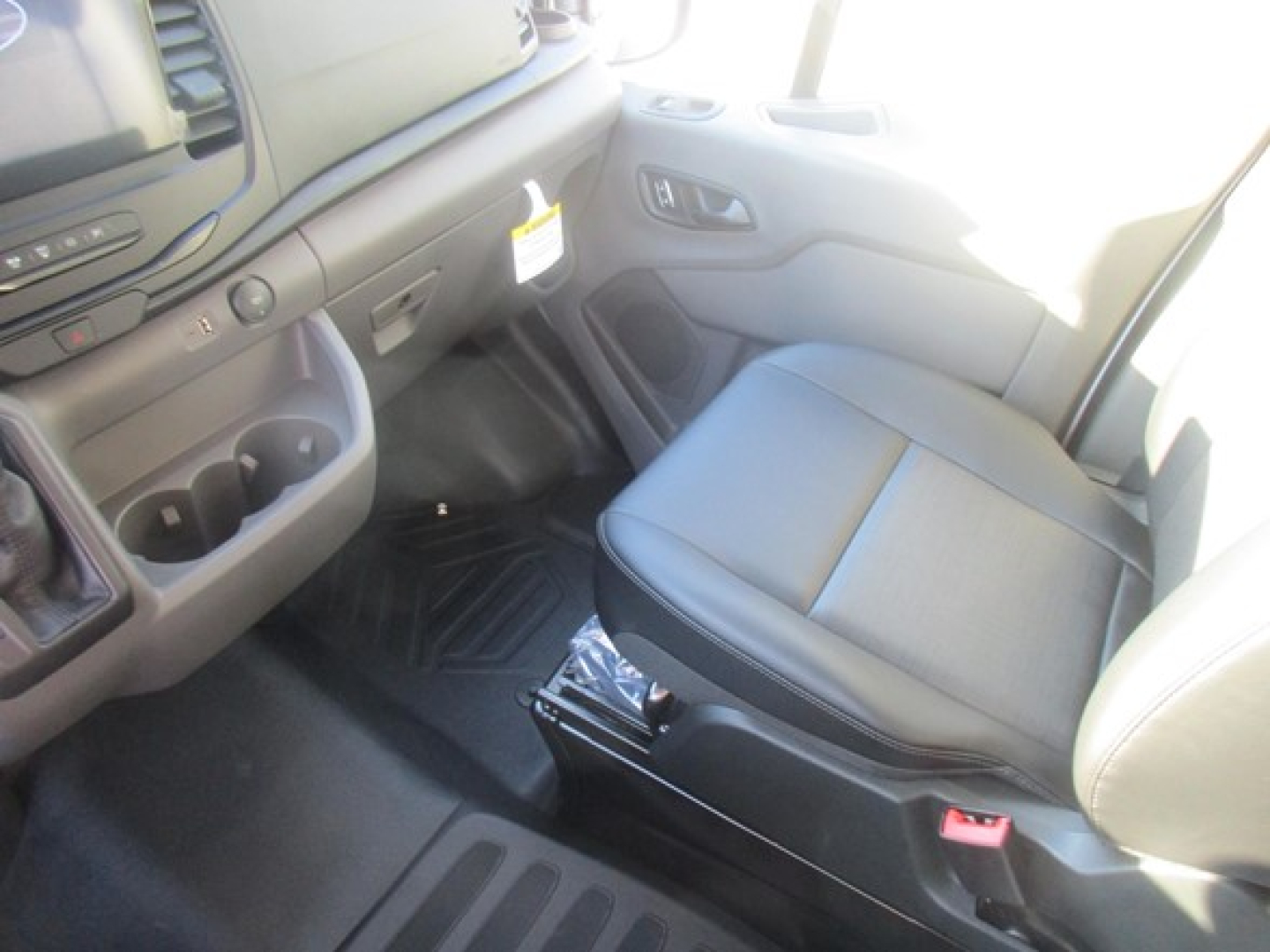 Ford Transit cargo van interior showing driver seat and front dashboard area with cup holders and controls.