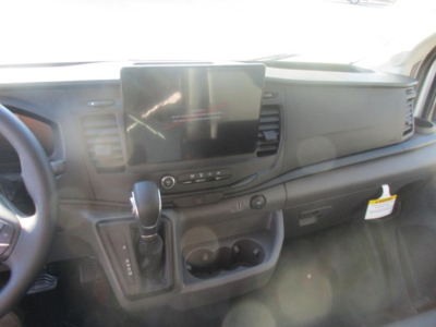 Ford Transit cargo van interior showing center infotainment screen, steering wheel, gear shifter, and dashboard controls.