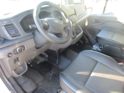 Ford Transit cargo van interior view showing steering wheel, dashboard, and front seats from the driver side.