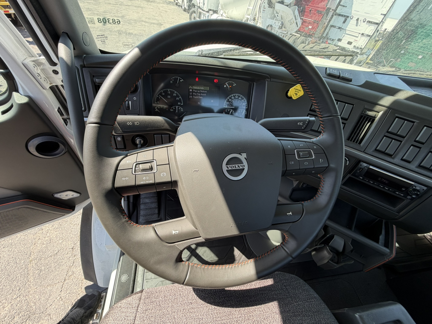 Volvo steering wheel and dashboard in a new Volvo VHD64B300 mixer truck interior showing steering wheel controls and instrument cluster.