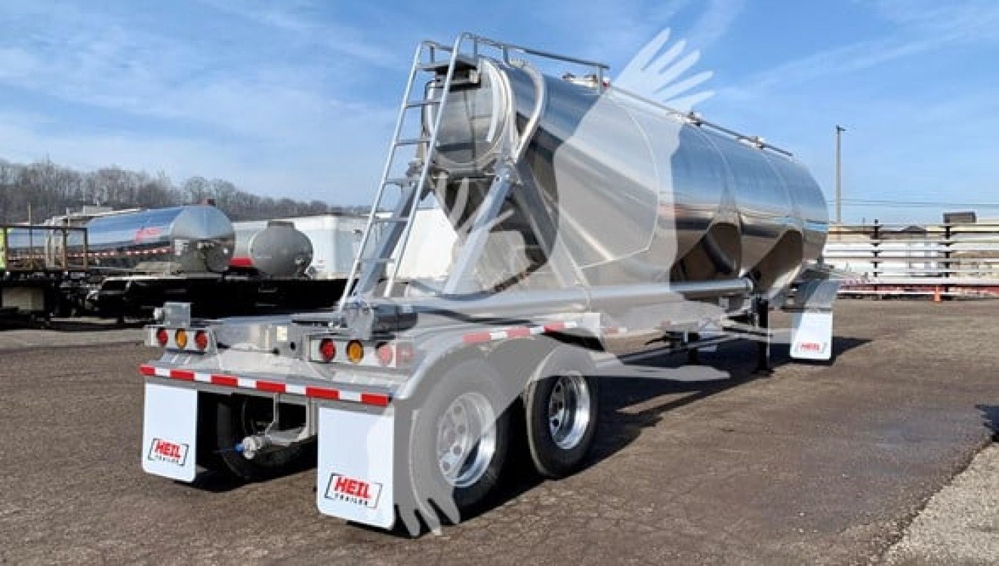 Heil Cementer pneumatic trailer showing stainless steel cylindrical tank and rear dual-axle configuration with mud flaps and decals.