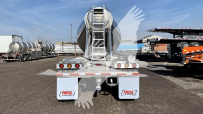 Trailer rear view of a new Heil cementer pneumatic dry bulk trailer showing rear lights, mud flaps with Heil branding, and a central hose discharge chute.