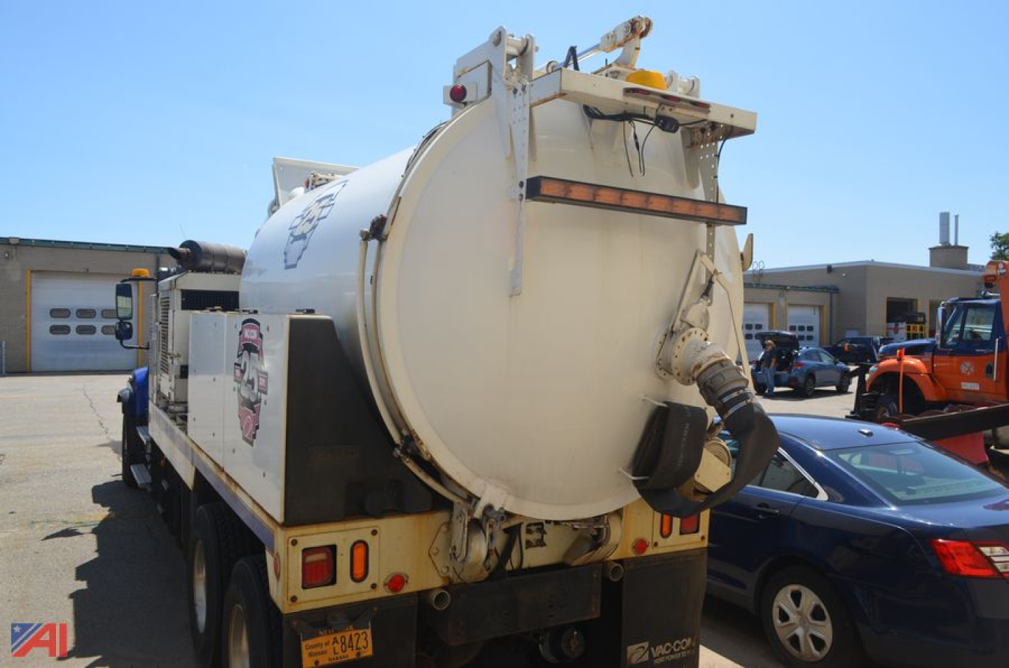 Rear view of a white Freightliner 114 SD vacuum truck showing rear vacuum tank and hoses.