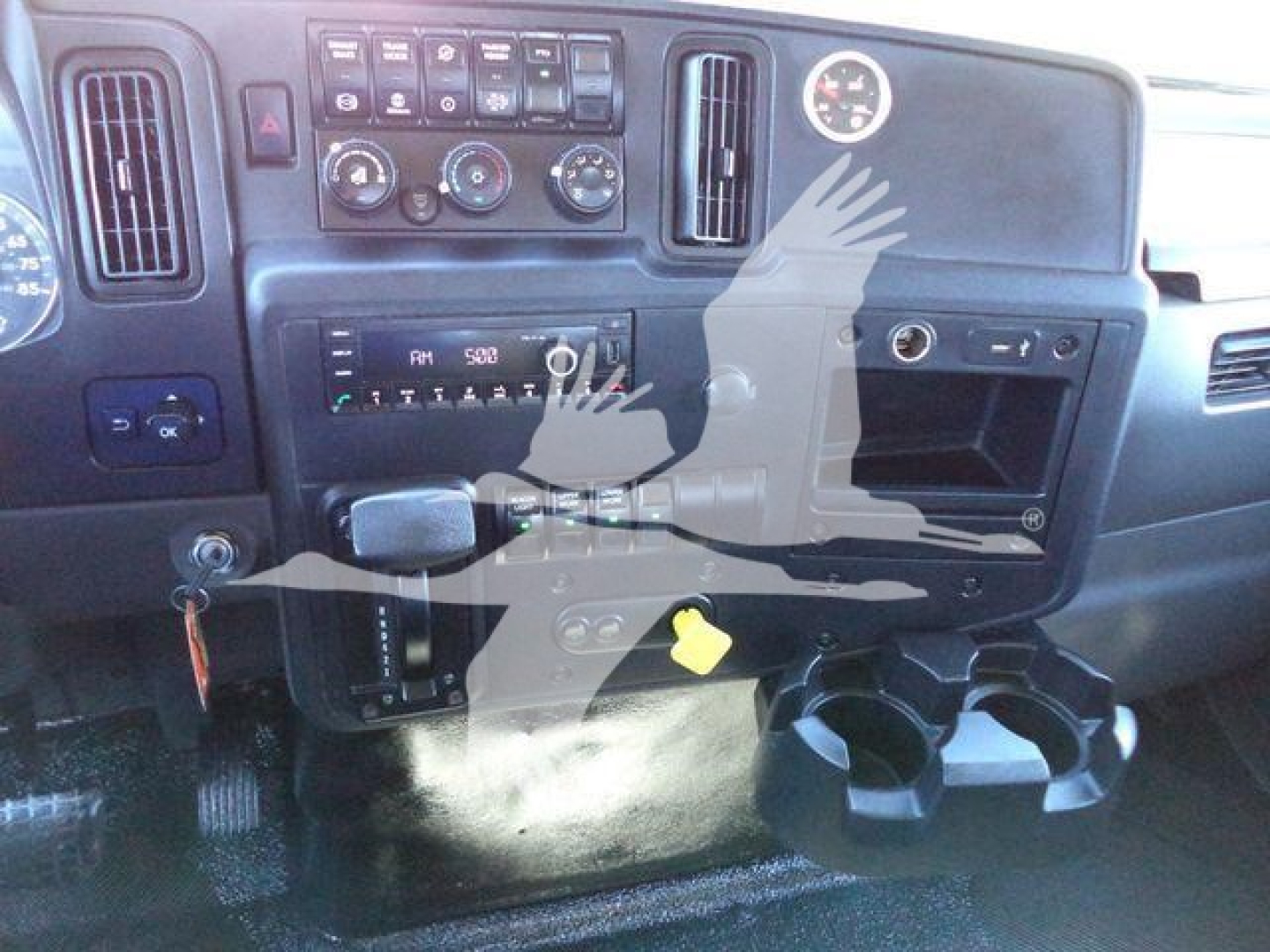 Dashboard center of a 2022 International MV rollback truck showing gauges, controls, radio, air vents, cup holders, and ignition area.