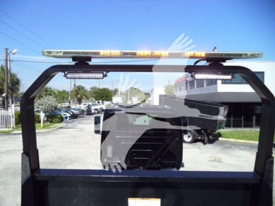 Truck rollback bed frame visible through rear window of a 2022 International MV; rooftop amber warning light bar; side mirrors; dealership lot in background.