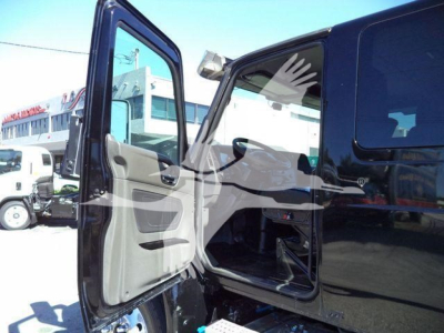 Truck cab interior view with open door showing gray fabric and black dashboard, entry step, and side mirror; part of a black 2022 International MV rollback truck.