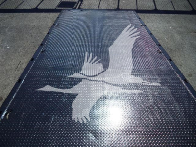 Tractor-trailer/rollback truck bed with a bird graphic on a diamond plate surface, showing edge latches and textured metal.