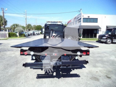 Tow truck bed area of a rollback truck showing flatbed and rear chassis with lights and hitch.